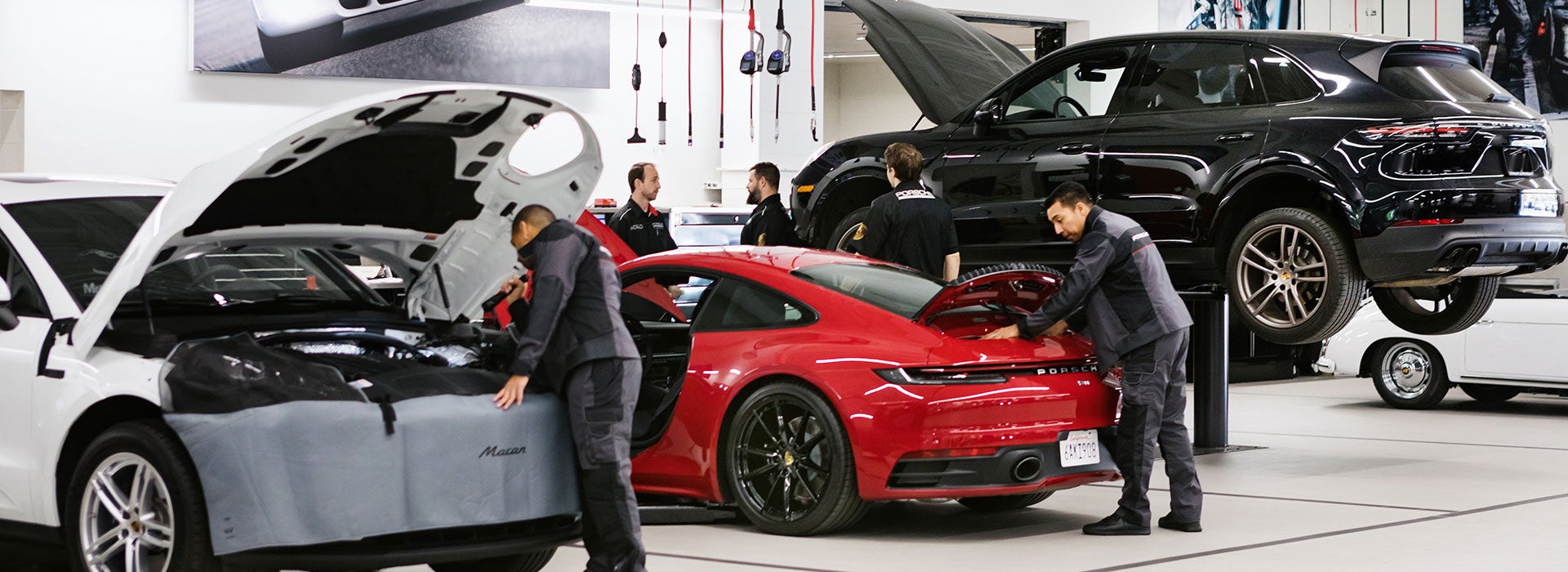 A mechanic works on a car engine inside a Porsche service center.