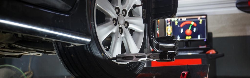 A car tire being aligned with a machine showing alignment data on a screen.