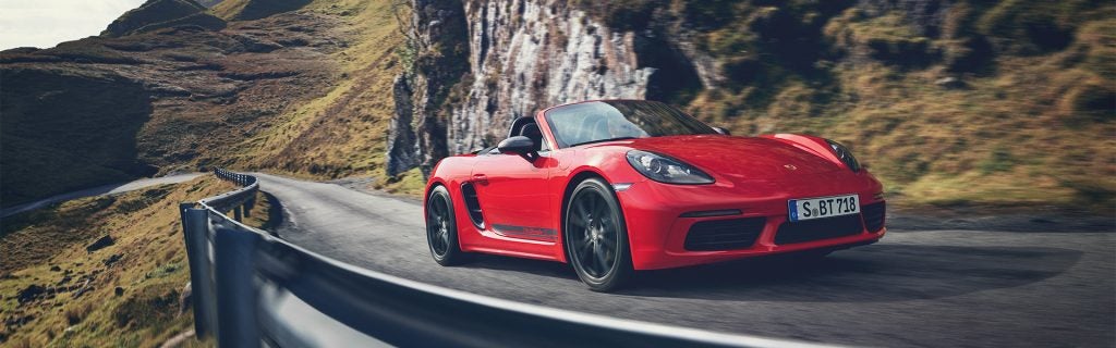 Red Porsche 718 Boxster driving on a winding mountain road