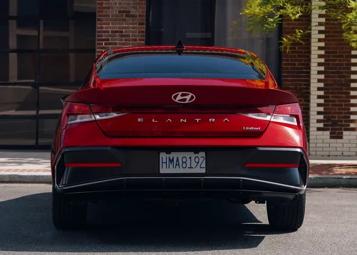 Red Hyundai Elantra sedan seen from the rear, parked on a city street.