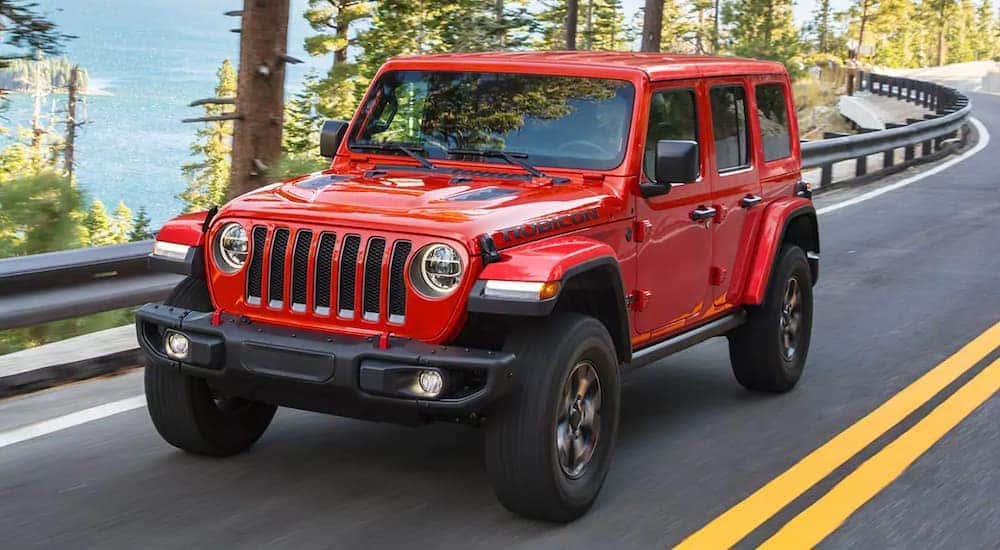 A red 2021 Jeep Wrangler is shown driving down a two lane road.