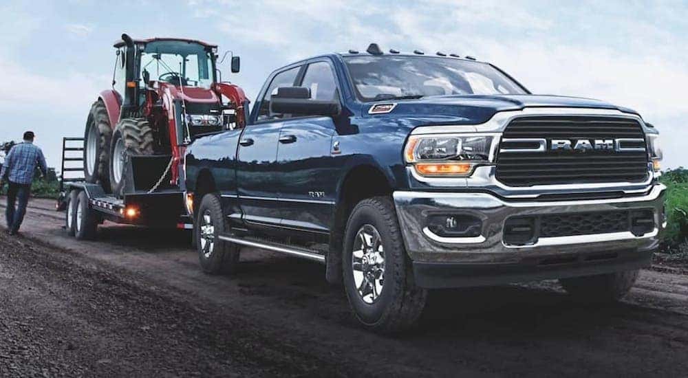 A blue 2021 Ram 2500 HD is shown towing a trailer after visiting a used Ram dealership in KY.