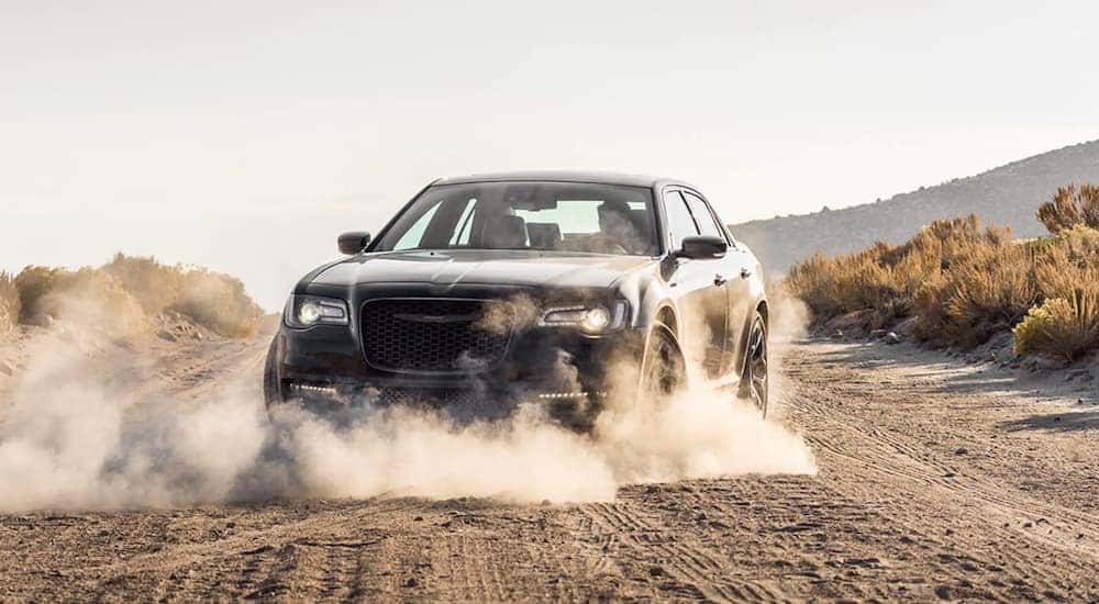 A black 2021 Chrysler 300 is shown kicking up dust on a dirt road after leaving one of the car dealerships in Georgetown, KY.