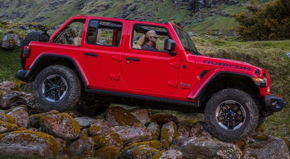 A red 2020 used Jeep Wrangler Rubicon is off-roading over rocks.