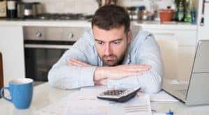 A man is sitting with his arms crossed in front of paperwork.