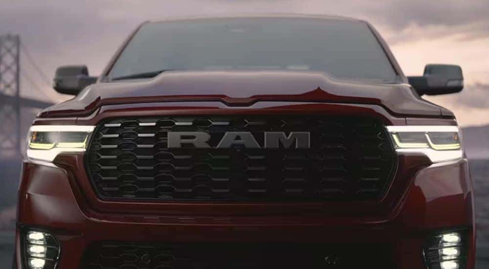 Close-up of the grille and headlights of a red 2025 Ram 1500 Tungsten.