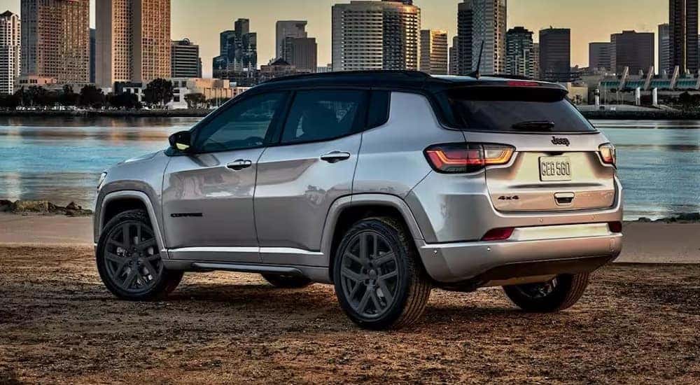 A silver 2024 Jeep Compass is shown parked near a city.