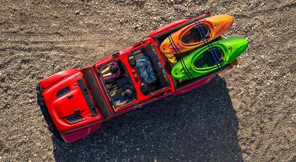 A red 2021 Jeep Gladiator is shown from above with its top off and kayaks in the bed.