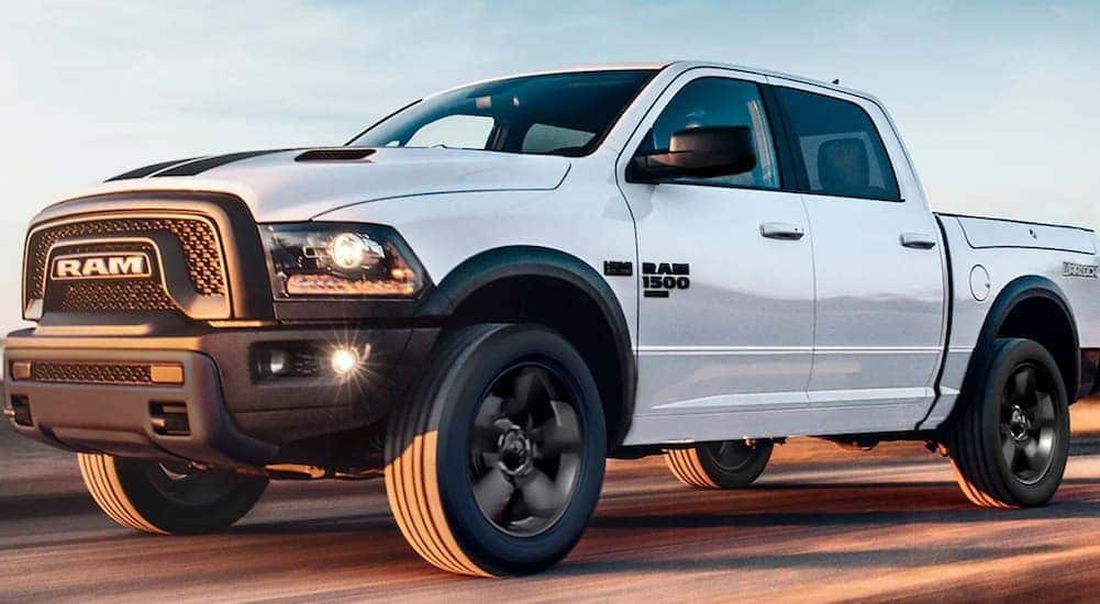 A white 2020 Ram 1500 is shown from the side driving after leaving a used Ram truck dealership in Lexington.