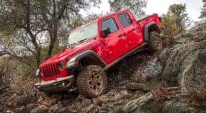 A red 2020 used Jeep Gladiator Rubicon is shown driving down rocks.