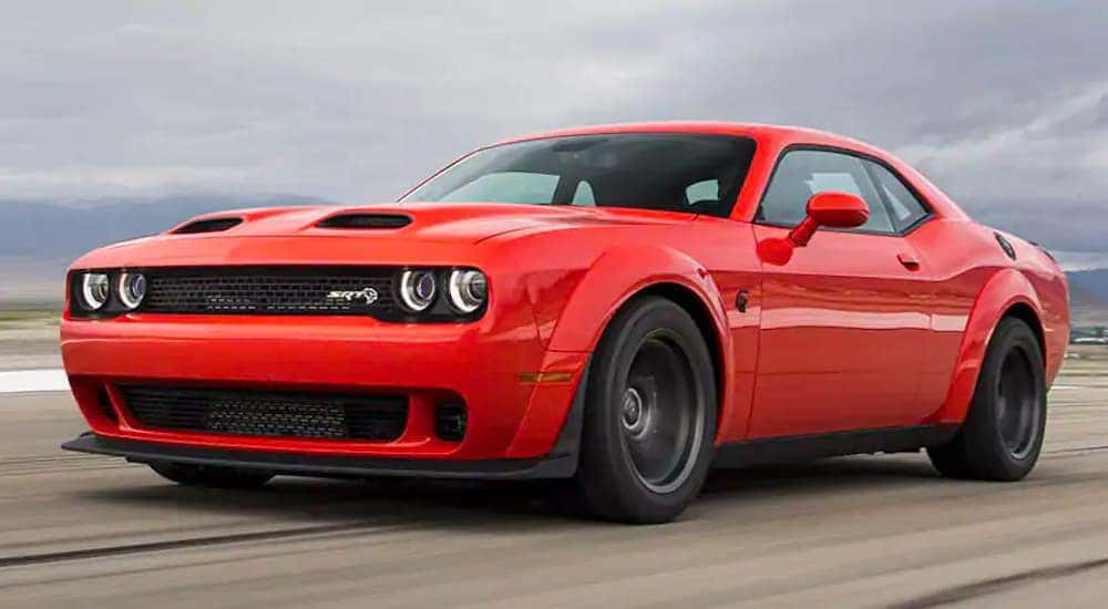An orange 2020 used Dodge Challenger is shown from the side driving down the road.