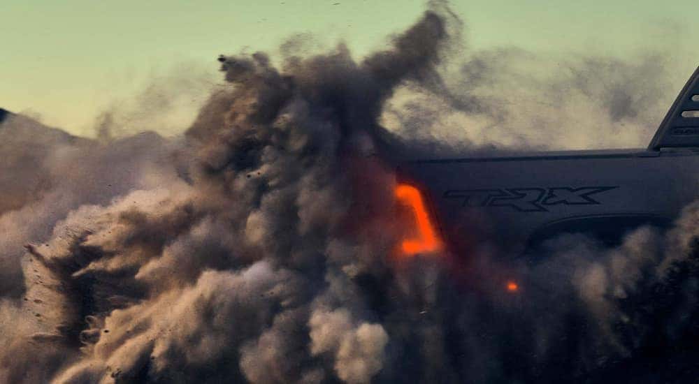 The tail light of a 2021 Ram TRX shows through a cloud of sand.