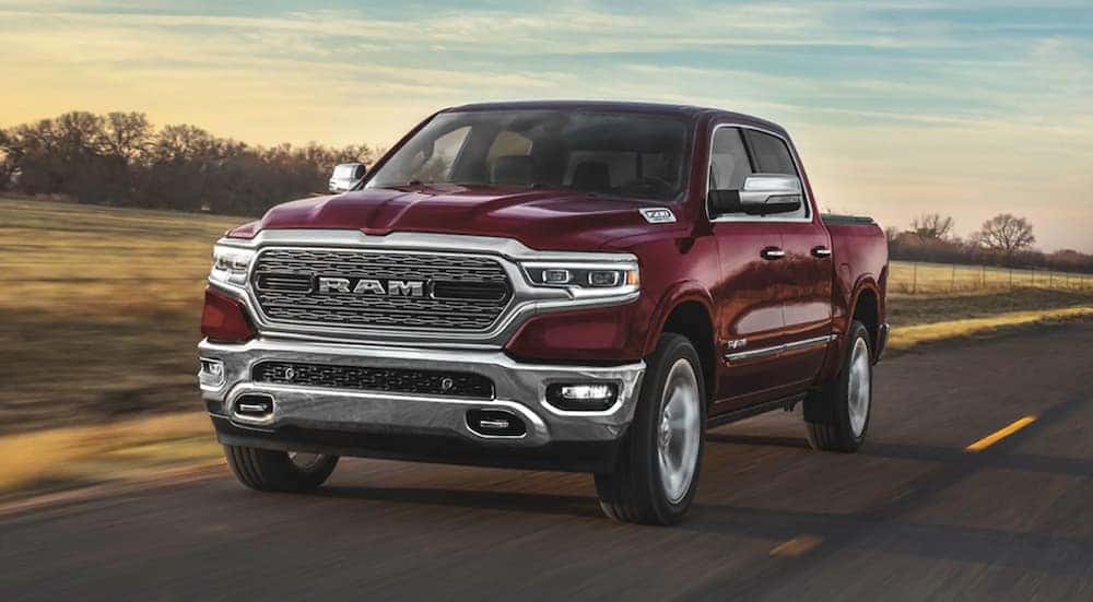 A burgundy 2020 Ram 1500 is driving past fields.
