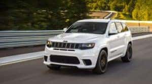 A white 2020 used Jeep Grand Cherokee Trackhawk is shown driving past a guard rail.