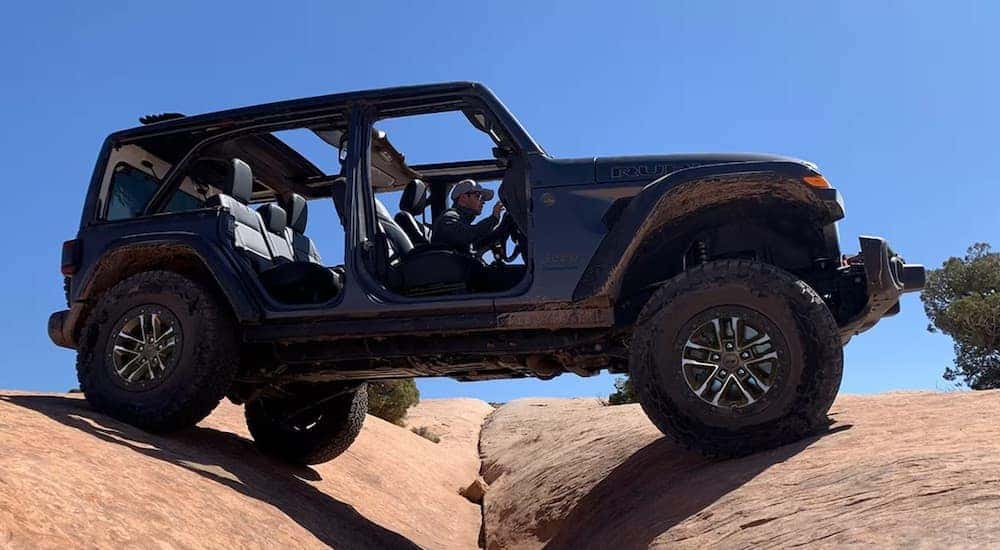 A grey 2024 Jeep Wrangler Rubicon X is shown from the side while off-road.