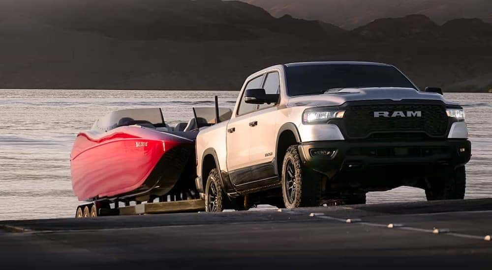 A silver 2025 Ram 1500 towing a boat out of a body of water.