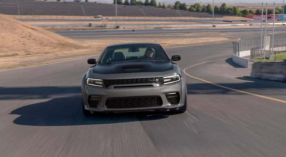 A grey and black 2023 Dodge Charger Scat Pack Widebody is shown driving on a track.