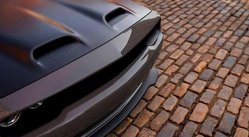 The hood of a gray 2020 used Dodge Challenger is shown from a high angle parked on a brick path.
