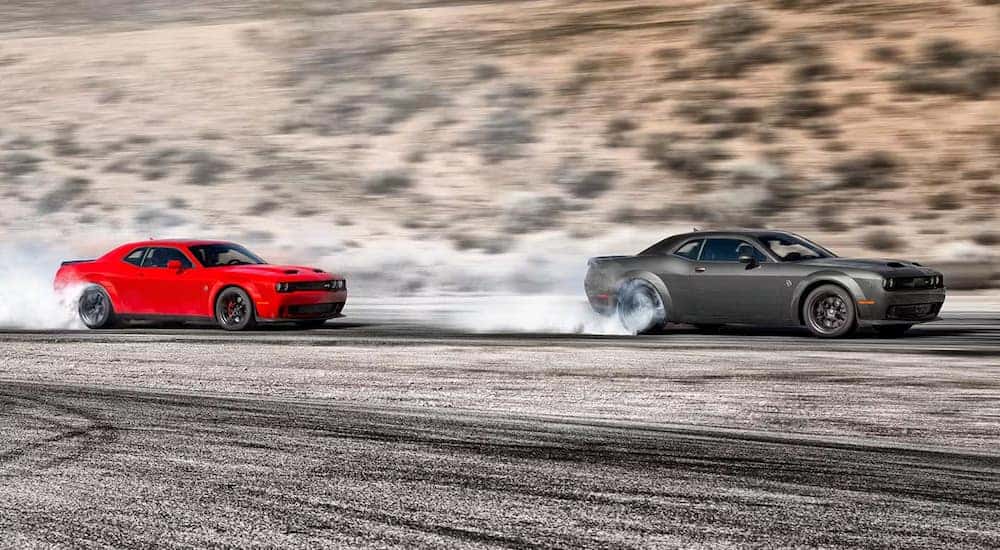 A grey and a red 2023 Dodge Challenger Hellcat are shown racing.