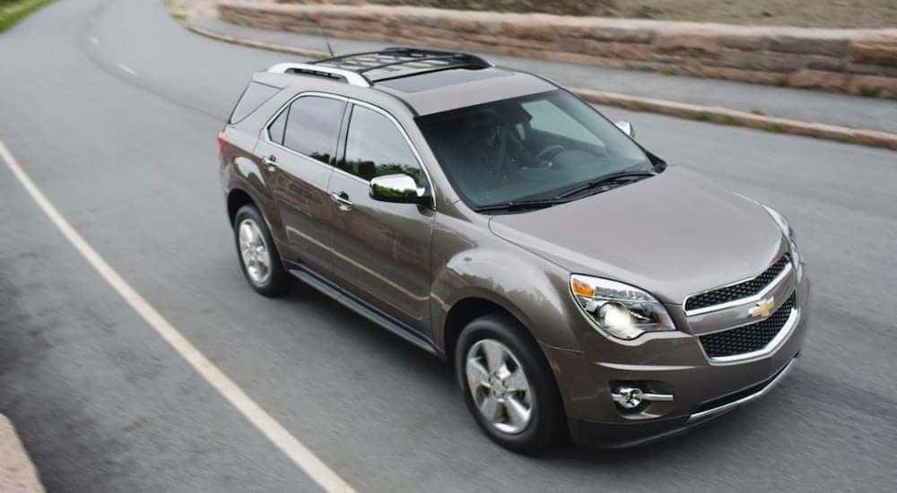 A grey 2012 Chevy Equinox is driving on a road past a stone wall near Lexington, KY.