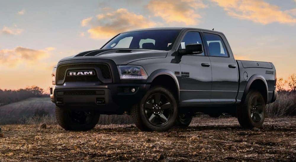 A grey 2019 Ram 1500 Classic, which is popular among used trucks for sale, is parked off-road at sunset in Lexington, KY.