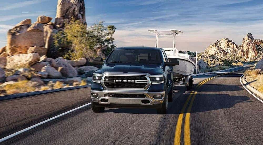 A blue 2023 Ram 1500 is shown front the front while towing a boat after leaving a Ram dealer near Lexington.