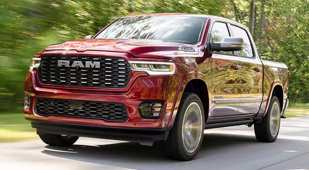 A red 2025 Ram 1500 for sale near Independence driving by a forest.