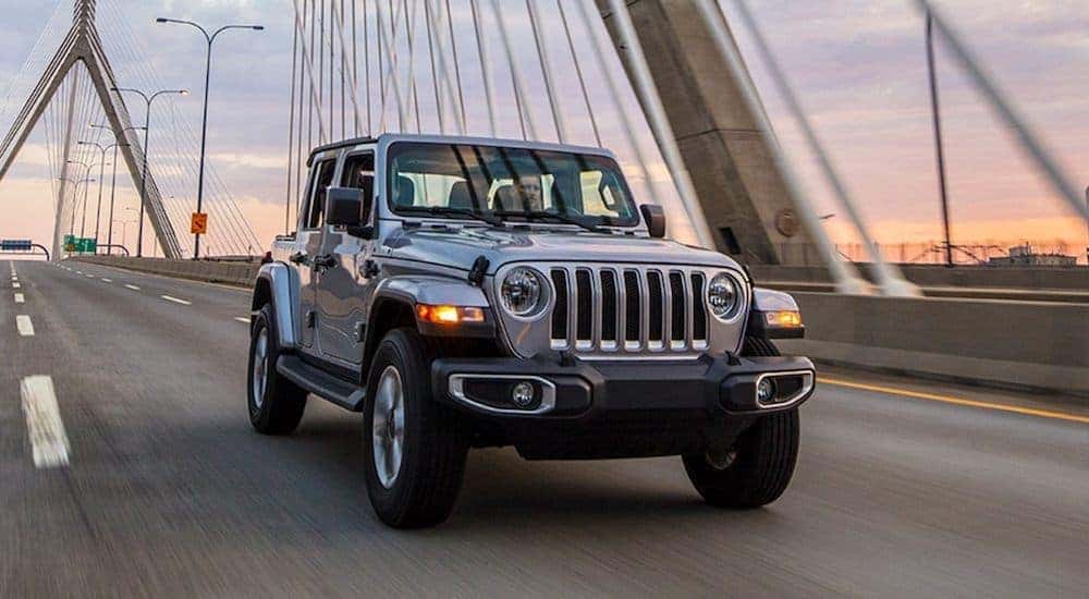 A silver 2020 Jeep Wrangler Sahara is shown driving over a bridge after leaving a used Jeep dealer in KY.