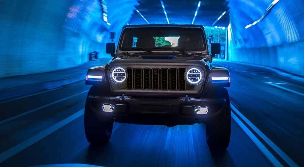 A silver 2024 Jeep Wrangler Rubicon 4xe is shown from the front while driving through a tunnel.