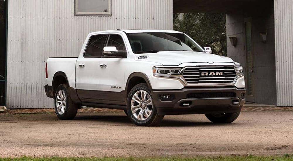 A white 2020 Ram 1500 is parked in front of a metal building.