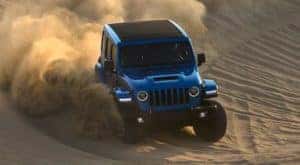 A blue 2022 Jeep Wrangler Rubicon Xtreme Recon is shown off-roading in the desert.