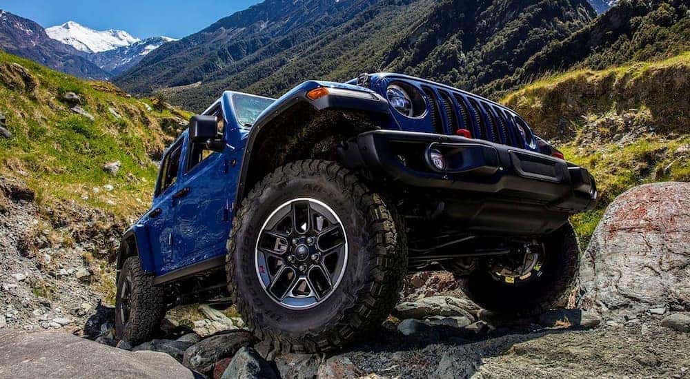 A blue 2019 used Jeep Wrangler Rubicon is off-roading on rocky terrain.