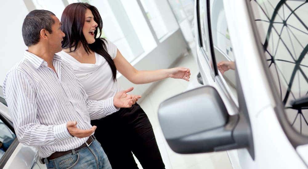 An excited couple is shown looking for cars at a used car dealer in Lexington.