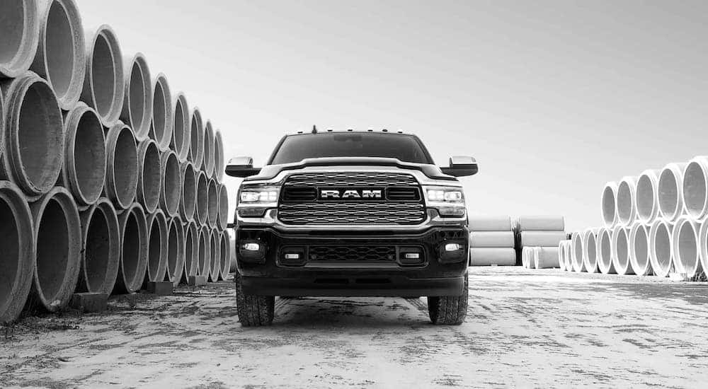 A black and white photo shows a black 2019 Ram 2500 surrounded by concrete pipes and shown from a low angle.