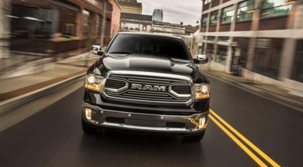 A black 2015 Ram 1500 is shown driving on a city street.