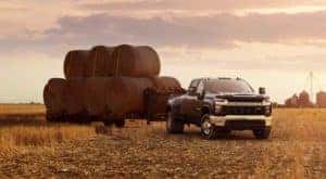 A black 2020 Chevy Silverado 3500HD is shown parked in a field towing hay bails.