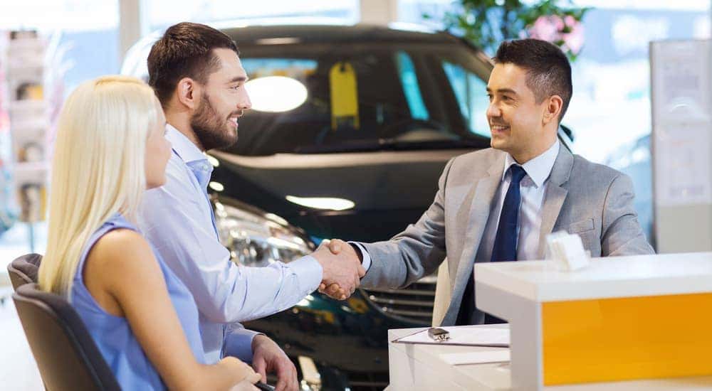 A salesman and buyer are shaking hands after the couple bought a car in a Lexington dealership.