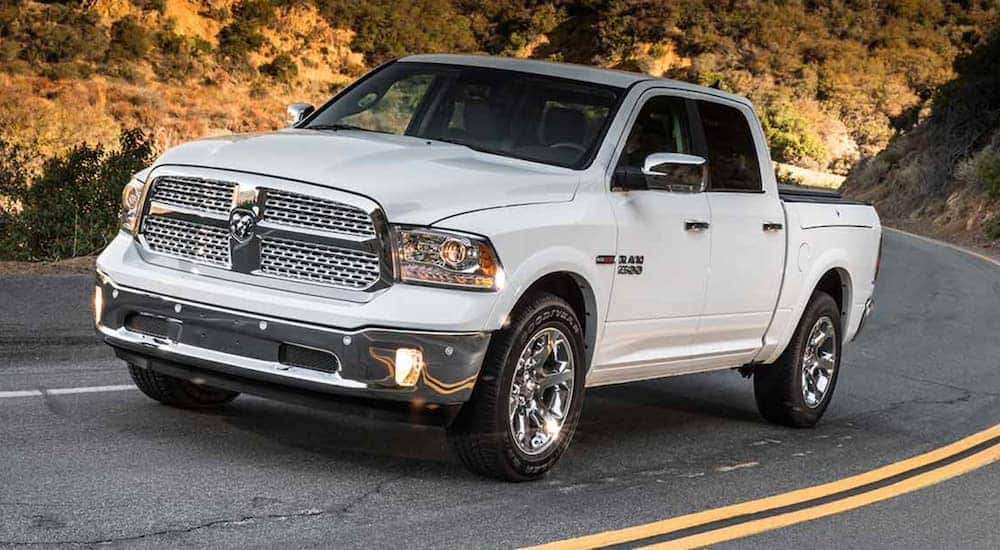 A white 2012 Ram 1500 is shown driving on a highway after visiting a used Ram dealership.