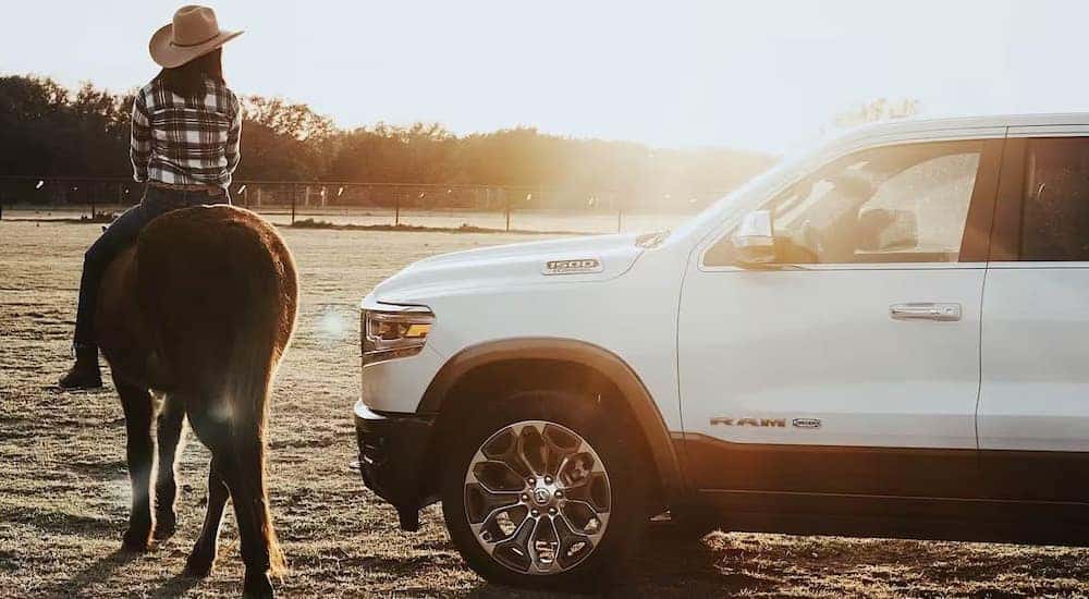 A white 2024 Ram 1500 is shown parked near a person riding a horse.