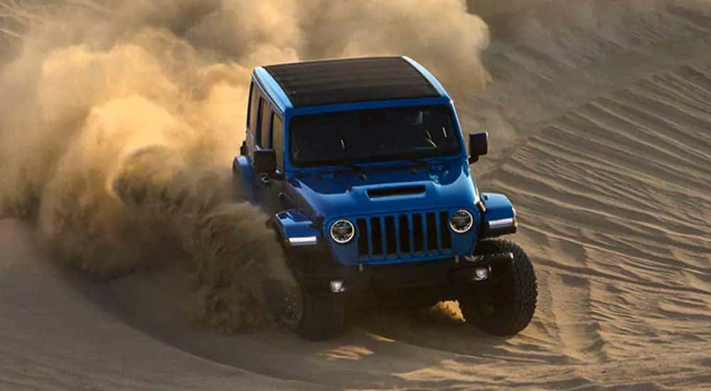 A blue 2021 Jeep Wrangler Rubicon 392 is off-roading on sand.
