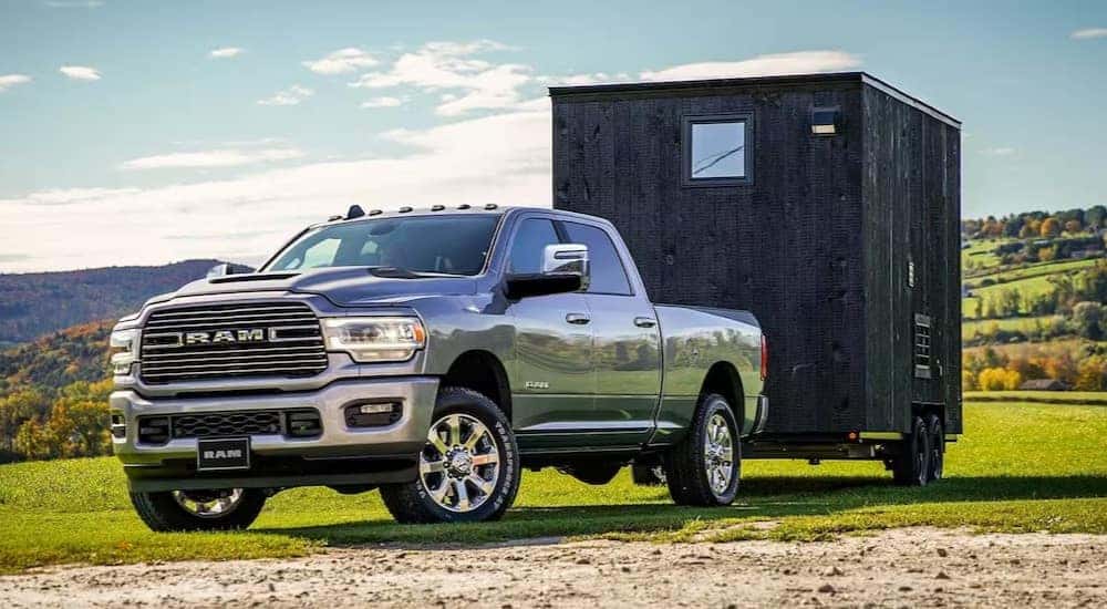 A silver 2023 Ram 2500 Laramie is shown towing a shed.