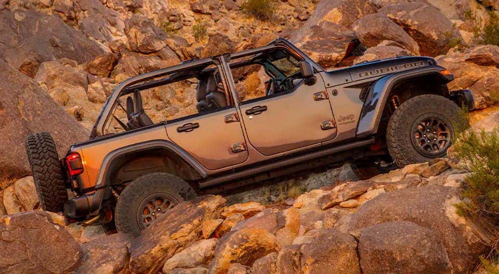 A grey 2021 Jeep Wrangler Rubicon 392 with no roof is off-roading on a rocky desert trail.