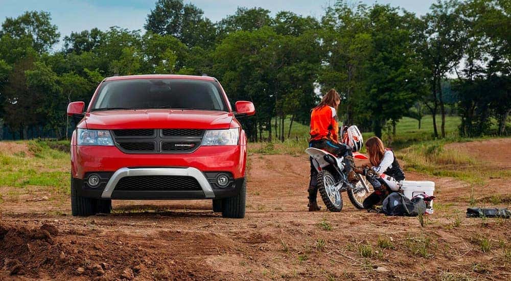 A red 2020 used Dodge Journey is shown from the front, parked next to a dirtbike.