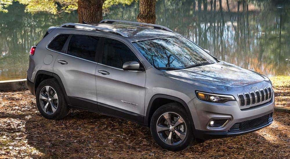 A silver 2020 Jeep Cherokee is parked in front of a pond.