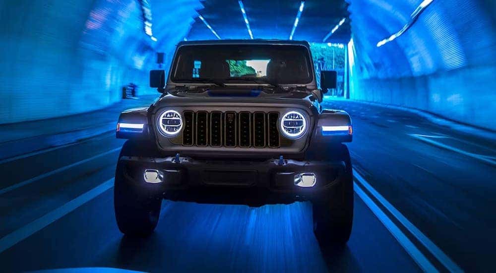 A front view of a grey 2024 Jeep Wrangler Rubicon 4xe driving through a tunnel.