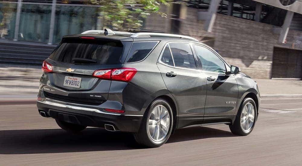 A grey 2020 Chevy Equinox is driving on a city street.