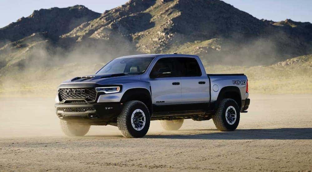 A silver 2025 Ram 1500 RHO parked in a dusty dirt area.