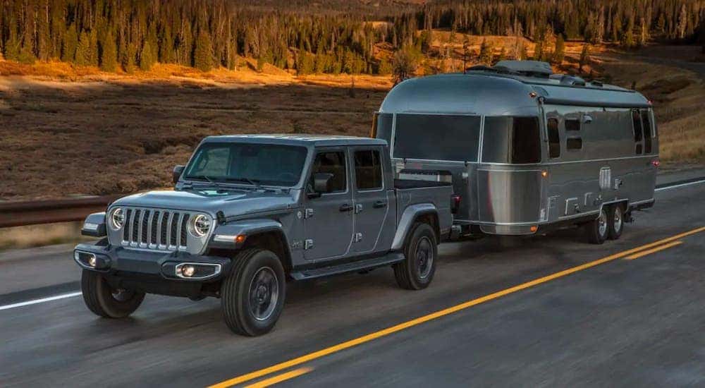 A silver 2019 used Jeep Gladiator is towing an Airstream trailer.