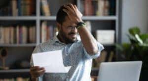 A man is hitting his forehead after looking at his credit score.