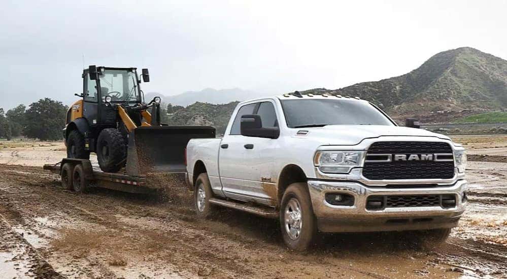 A white 2024 Ram 2500 Tradesman is shown towing a trailer to a Ram dealer near Covington.